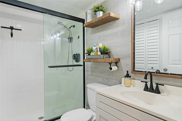 bathroom with a textured ceiling, toilet, vanity, and an enclosed shower