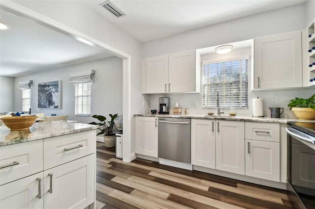 kitchen featuring sink, white cabinetry, stainless steel appliances, light stone counters, and light wood-type flooring