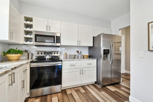 kitchen featuring decorative backsplash, light wood-type flooring, white cabinets, and appliances with stainless steel finishes