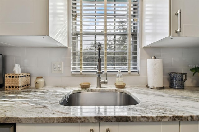 details featuring white cabinetry, sink, and light stone counters