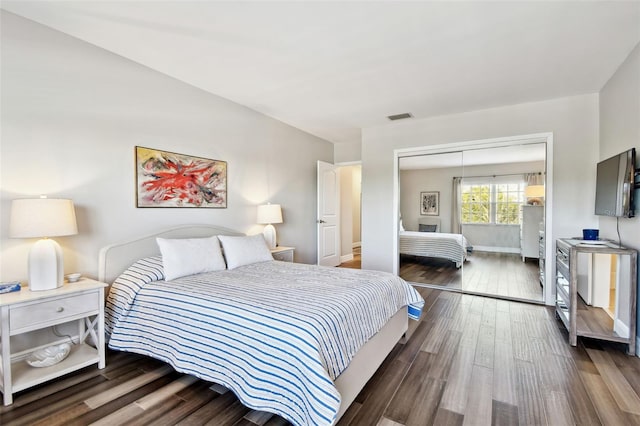 bedroom with dark wood-type flooring and a closet