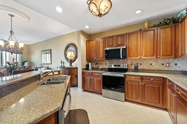 kitchen featuring stainless steel appliances, hanging light fixtures, sink, and light stone counters