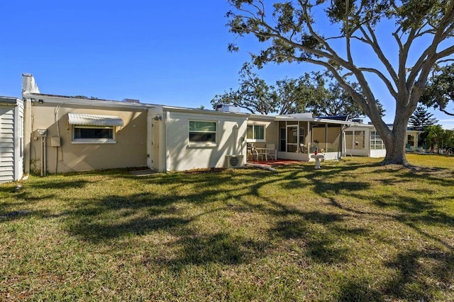 back of house featuring a sunroom and a lawn