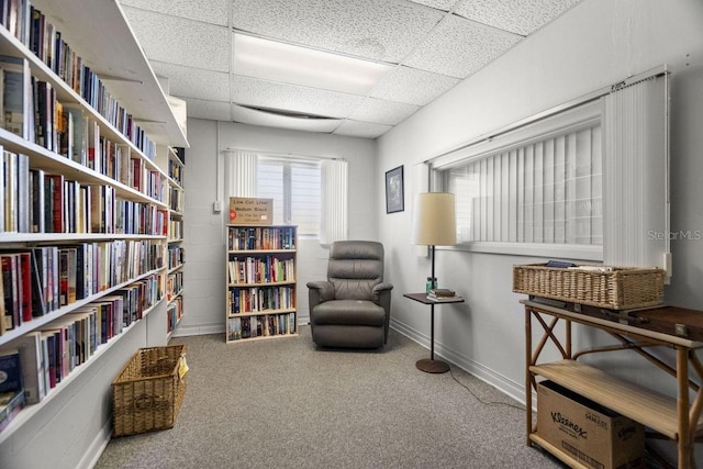 living area with carpet floors and a paneled ceiling