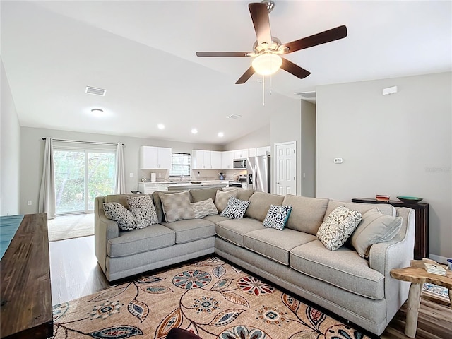 living room with light hardwood / wood-style floors, lofted ceiling, and ceiling fan