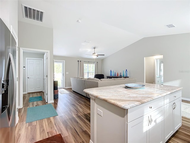 kitchen featuring stainless steel fridge with ice dispenser, white cabinets, a kitchen island, dark hardwood / wood-style flooring, and lofted ceiling