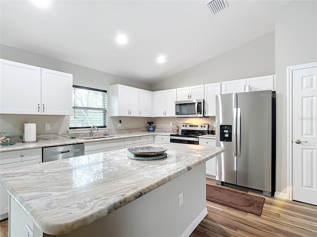 kitchen featuring a center island, lofted ceiling, white cabinetry, stainless steel appliances, and sink