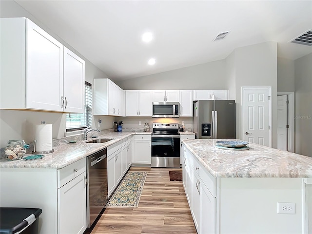 kitchen with white cabinets, a center island, lofted ceiling, stainless steel appliances, and sink