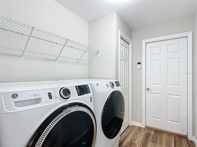 laundry room with a textured ceiling, light hardwood / wood-style flooring, and washing machine and dryer