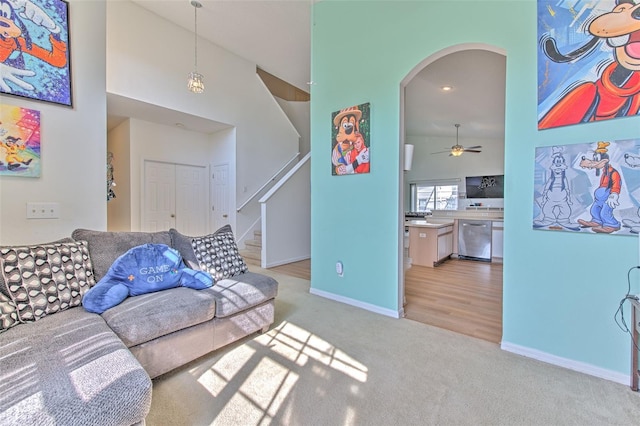 carpeted living room featuring ceiling fan and high vaulted ceiling