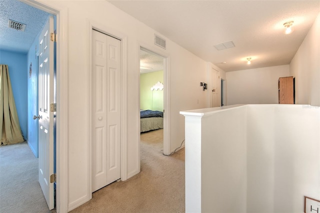 corridor featuring light carpet and a textured ceiling