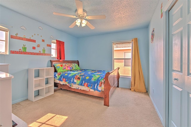 bedroom featuring multiple windows, ceiling fan, light carpet, and a textured ceiling