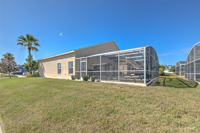 rear view of property with a yard, glass enclosure, and a patio area