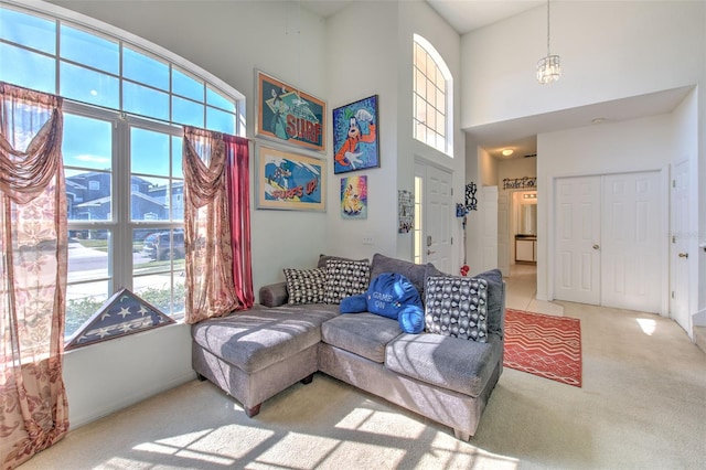 living room with a towering ceiling and light colored carpet