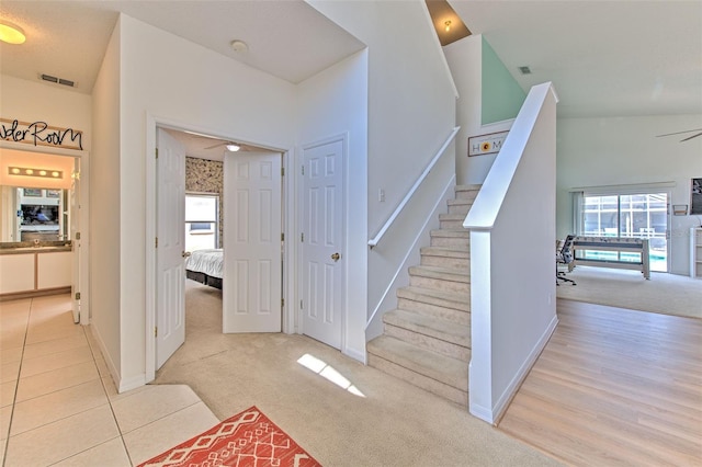 staircase with ceiling fan and carpet floors