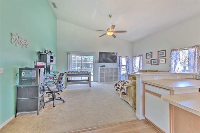 interior space with ceiling fan, plenty of natural light, high vaulted ceiling, and light carpet