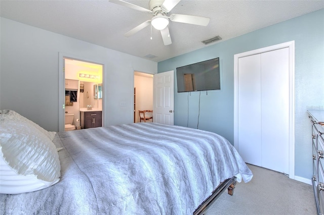 carpeted bedroom featuring ceiling fan, connected bathroom, and a textured ceiling