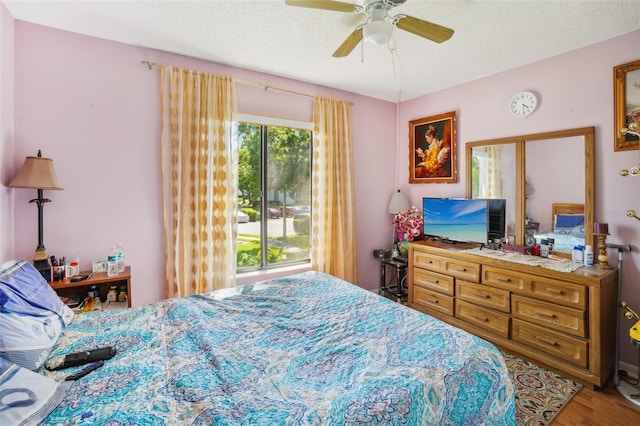 bedroom with hardwood / wood-style flooring, a textured ceiling, and ceiling fan