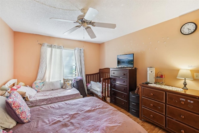 bedroom featuring ceiling fan, hardwood / wood-style floors, and a textured ceiling