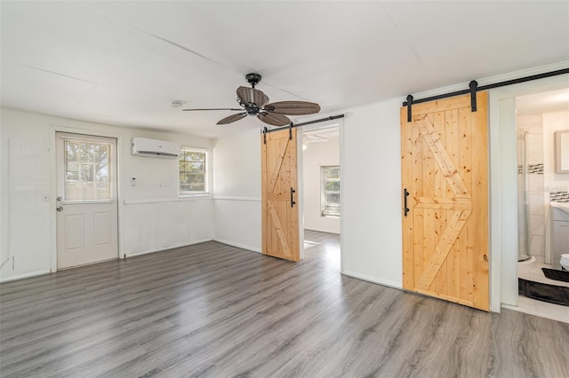 foyer featuring a wall mounted air conditioner, light hardwood / wood-style flooring, a barn door, and ceiling fan