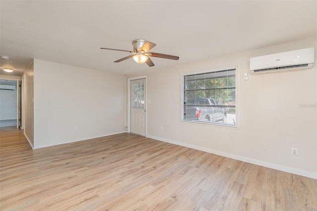 spare room featuring light hardwood / wood-style flooring, a wall unit AC, and ceiling fan