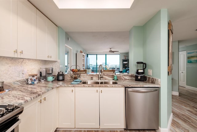 kitchen with light stone countertops, appliances with stainless steel finishes, white cabinetry, and sink