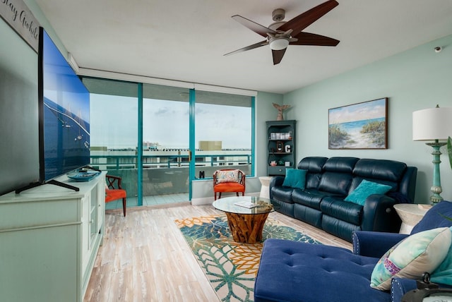 living room with floor to ceiling windows, ceiling fan, and light wood-type flooring