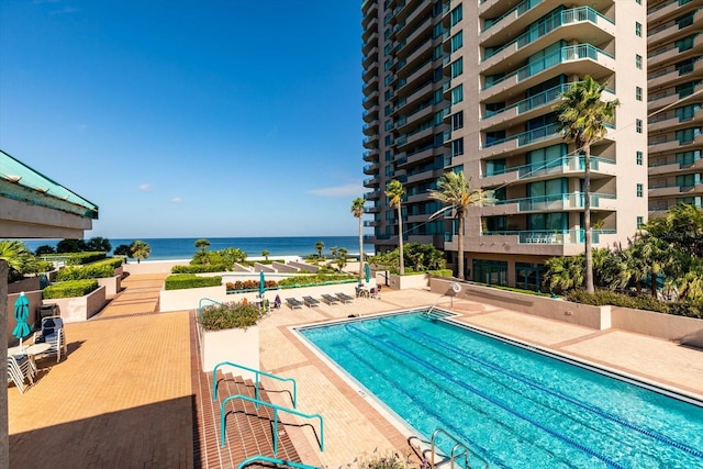 view of pool with a water view and a patio area