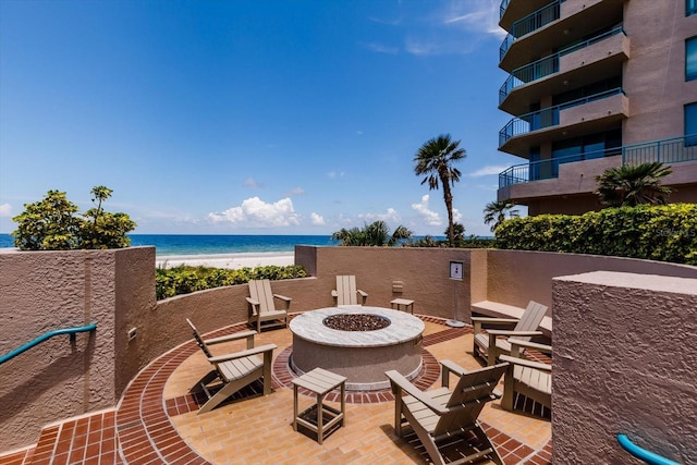 view of patio featuring a fire pit, a water view, and a view of the beach