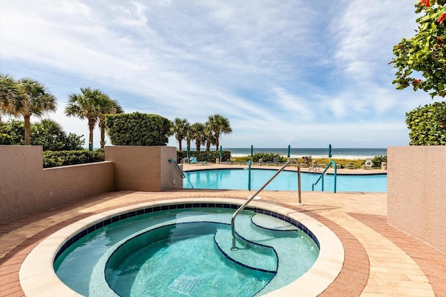 view of swimming pool featuring a hot tub and a water view