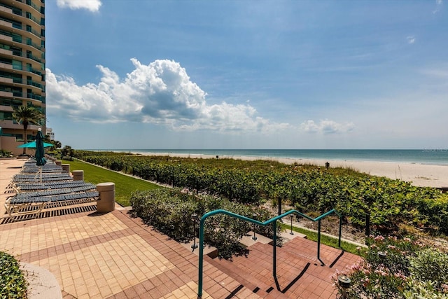 view of patio / terrace with a water view and a beach view