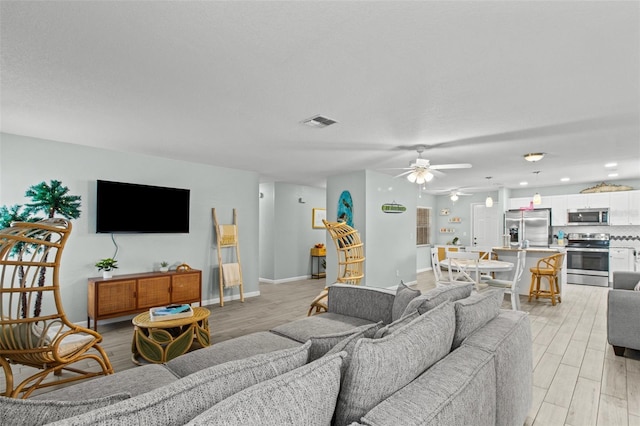 living room featuring ceiling fan and light hardwood / wood-style flooring