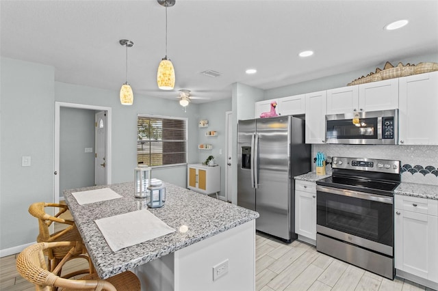 kitchen with decorative light fixtures, white cabinets, and stainless steel appliances