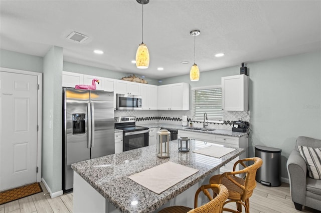 kitchen featuring a center island, decorative backsplash, sink, decorative light fixtures, and stainless steel appliances