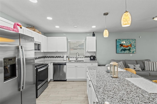 kitchen with sink, pendant lighting, white cabinets, and stainless steel appliances