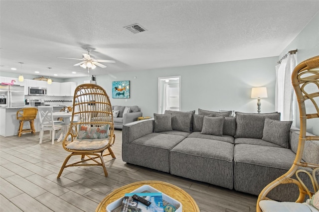 living room featuring ceiling fan and a textured ceiling