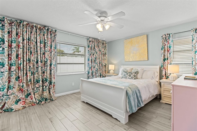 bedroom with light wood-type flooring, ceiling fan, and a textured ceiling