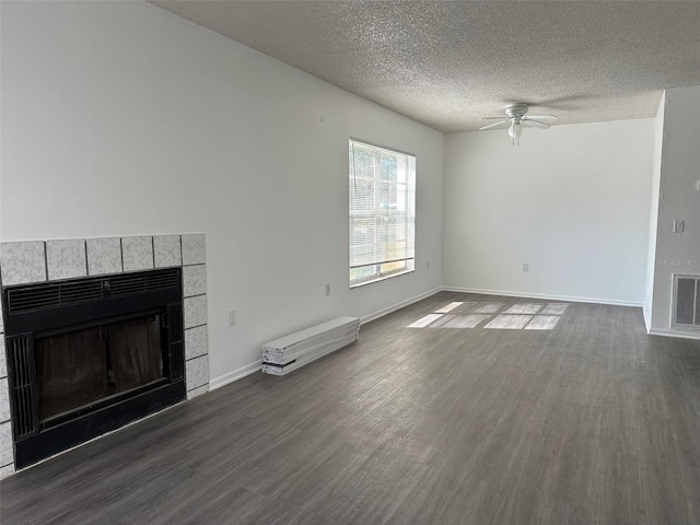 unfurnished living room featuring dark hardwood / wood-style flooring, a textured ceiling, ceiling fan, and a fireplace