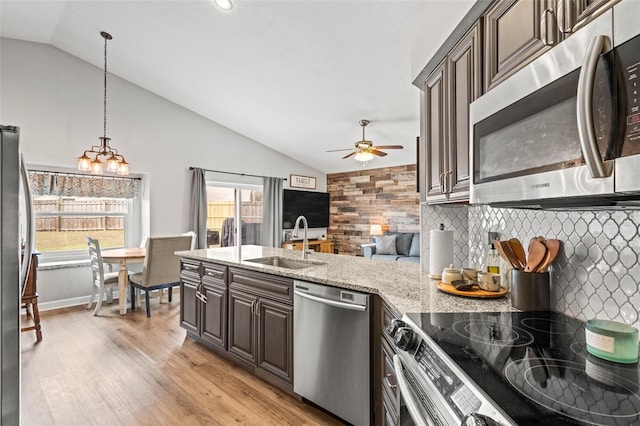 kitchen with stainless steel appliances, lofted ceiling, dark brown cabinetry, and sink