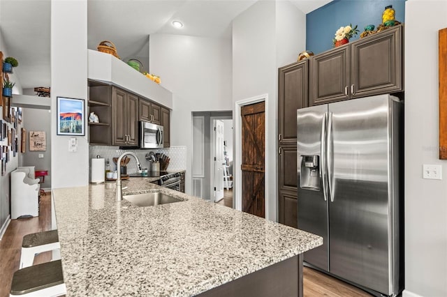 kitchen featuring kitchen peninsula, sink, appliances with stainless steel finishes, a breakfast bar area, and dark brown cabinets