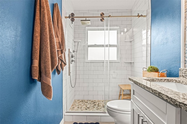 bathroom with a shower with shower door, toilet, vanity, and tile patterned flooring