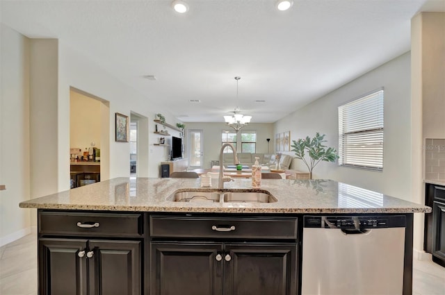 kitchen with an island with sink, dishwasher, sink, and light stone counters