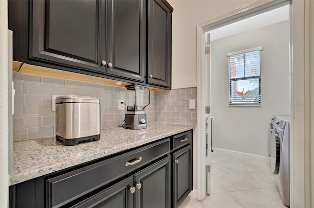 kitchen featuring decorative backsplash, light stone countertops, washer and dryer, and light tile patterned flooring