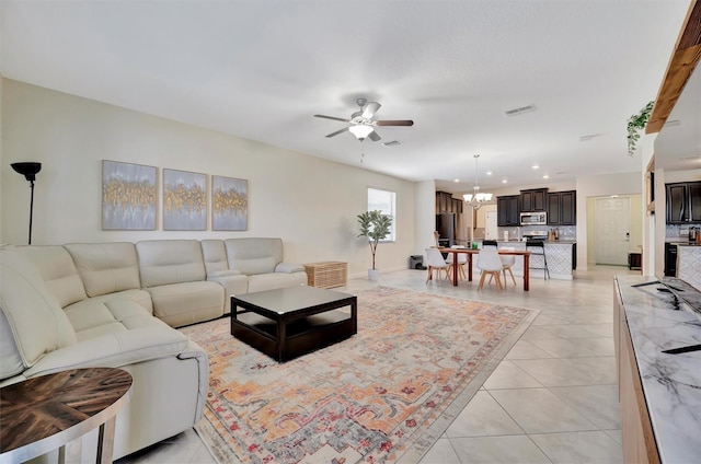 tiled living room with ceiling fan with notable chandelier