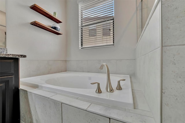 bathroom featuring vanity and tiled tub