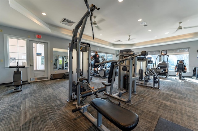 exercise room with a wealth of natural light, dark carpet, and a raised ceiling