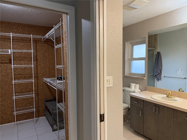 bathroom with a textured ceiling, tile patterned floors, vanity, and toilet