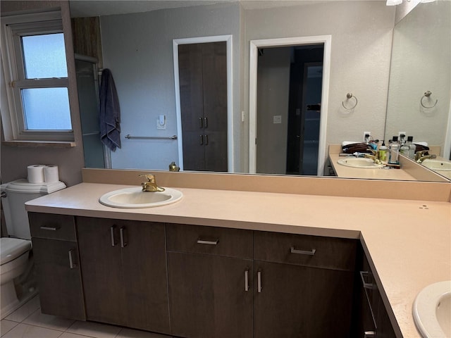 bathroom with tile patterned floors, vanity, toilet, and walk in shower