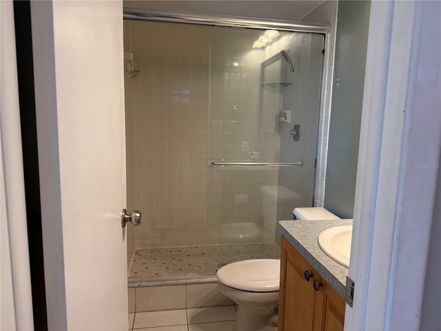 bathroom with vanity, toilet, a tile shower, and tile patterned flooring