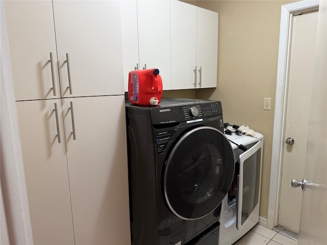 washroom with cabinets, light tile patterned floors, and washing machine and clothes dryer